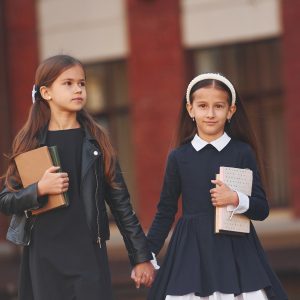 Walking together. Two schoolgirls is outside near school building